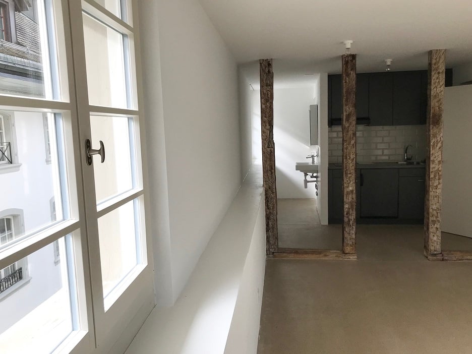 Empty room, white walls, wooden beams, sink, white door, large window