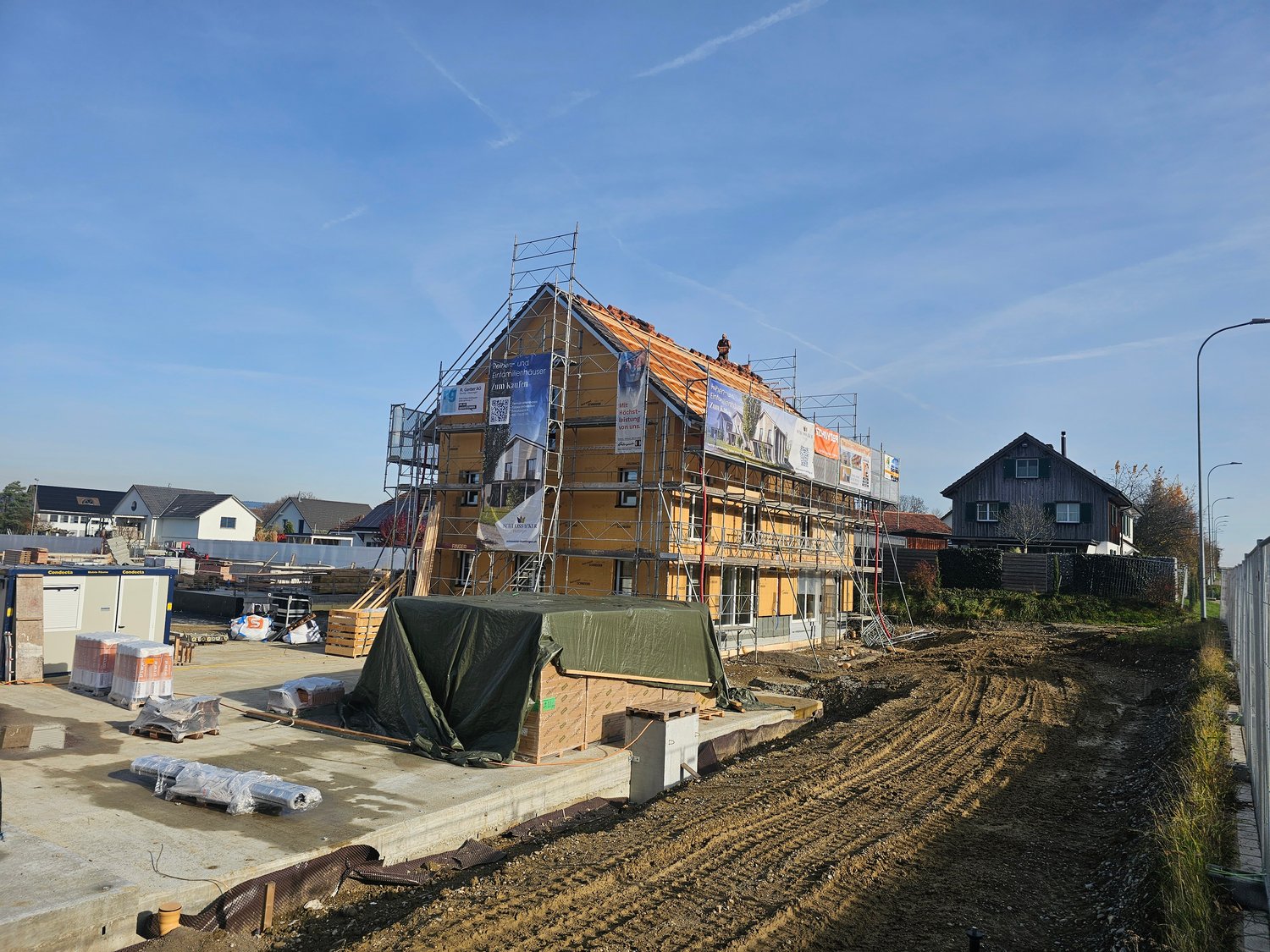 new house under construction, yellow exterior, wooden scaffolding, building materials around