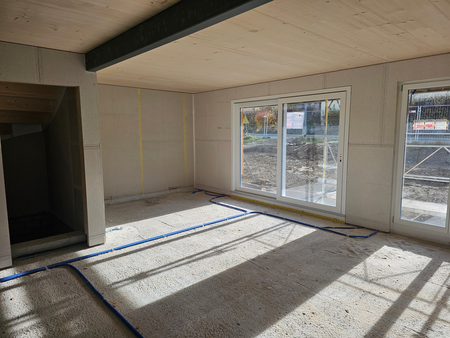 unfinished room, with staircase, double sliding doors, blue pipes on floor, yellow markings on wall