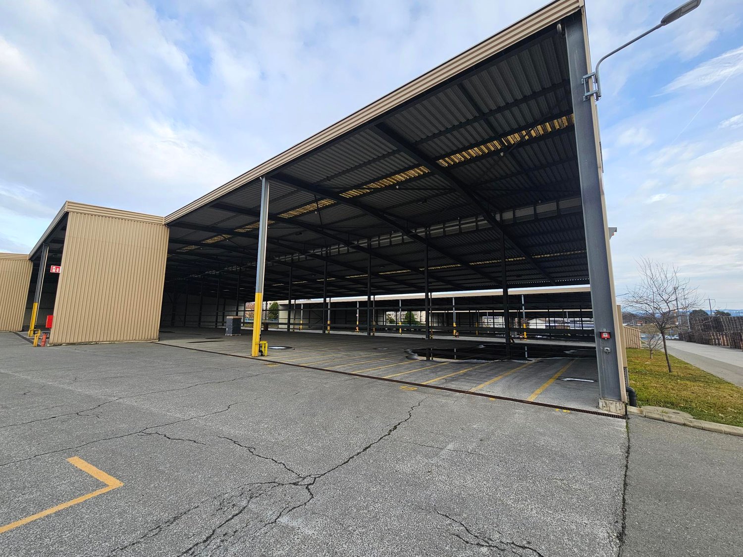 Metal roofing, columns, wide open space, paved floor, yellow road lines