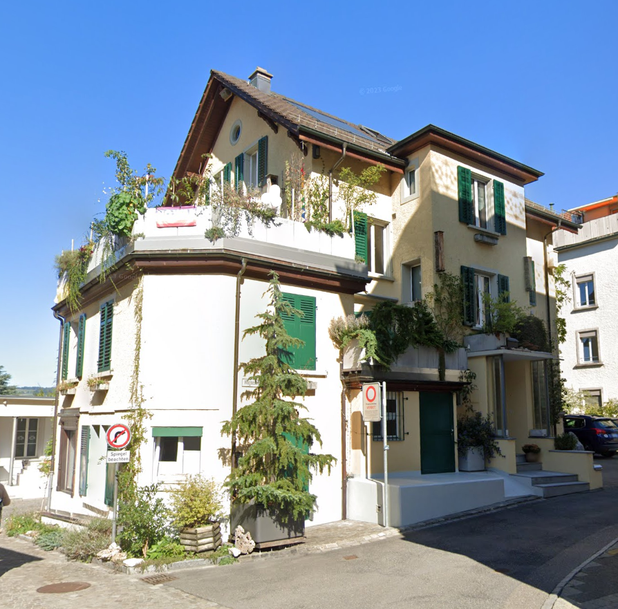 3 story house, white walls, green shutters, balconies, green plants, solar panels on the roof, street view