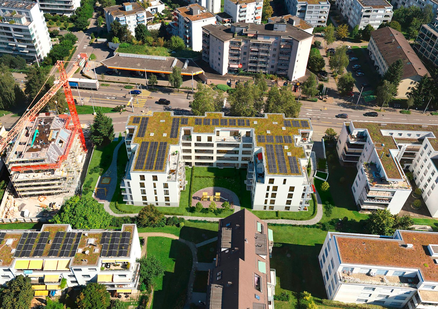 Aerial view of a residential building complex with multiple floors, large windows, and rooftop solar panels.