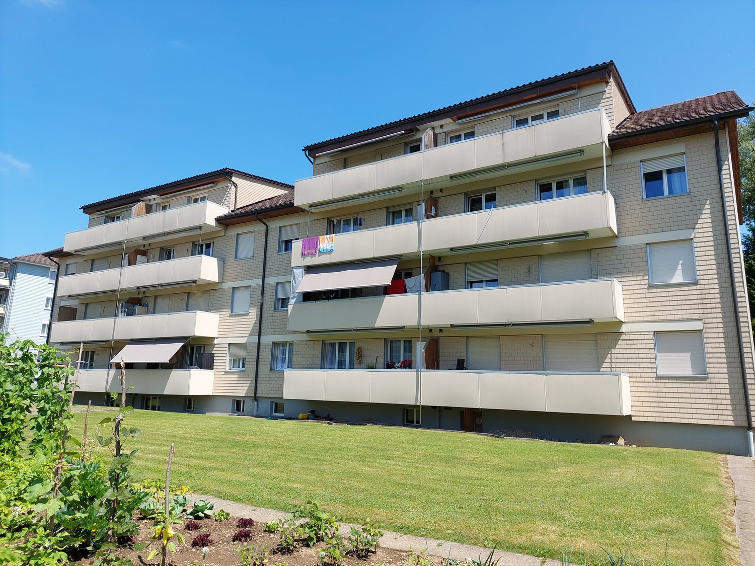 multi-story building, multiple balconies, green lawn in front