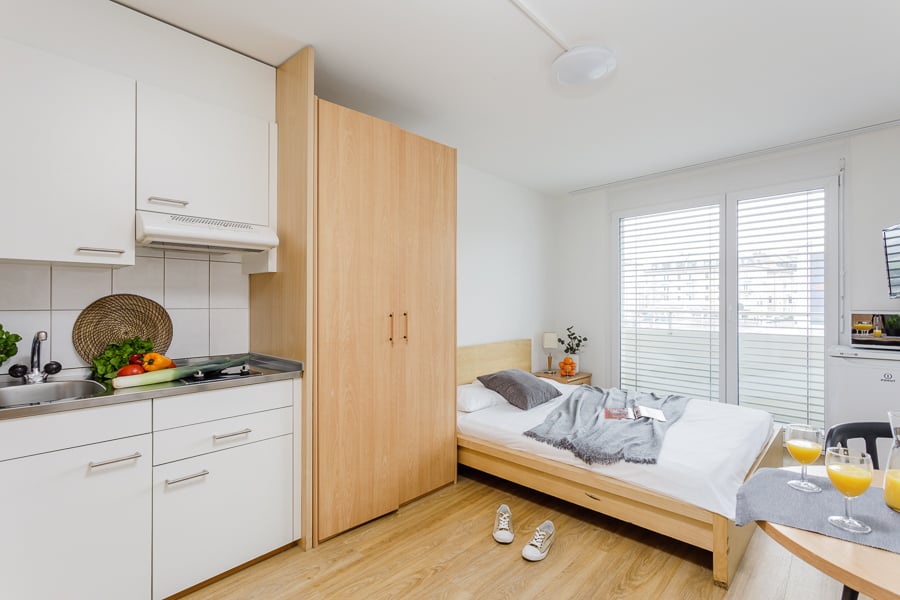 compact bedroom with bed, sink, counter, kitchen appliances, wardrobe