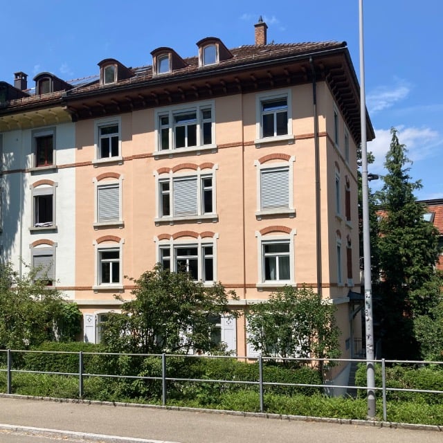 Apartment building, multiple windows, brown roof, balcony, chimney, metal fence