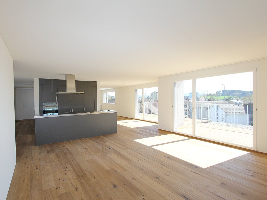 empty room, open kitchen, wooden floor, gray cabinets, balcony, large glass doors