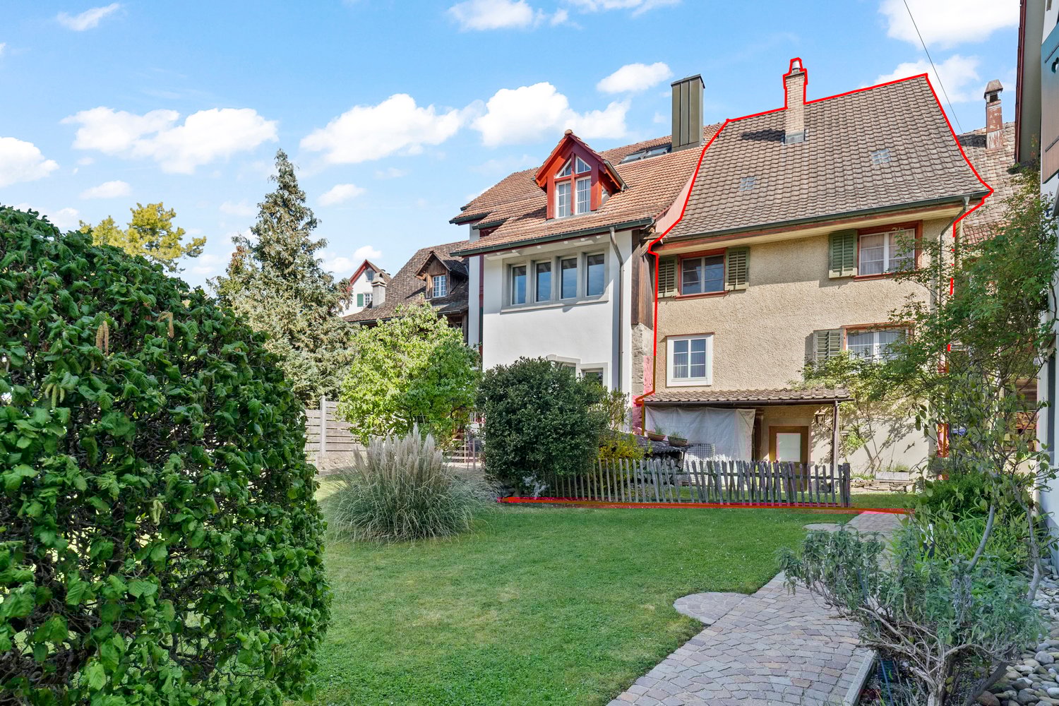 Three story house, red roof, brick exterior, windows, fenced garden