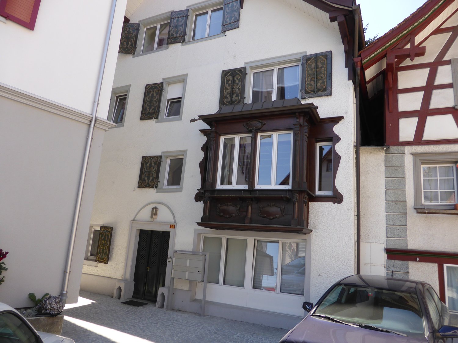 white building, multiple windows, wooden balconies, decorated entry