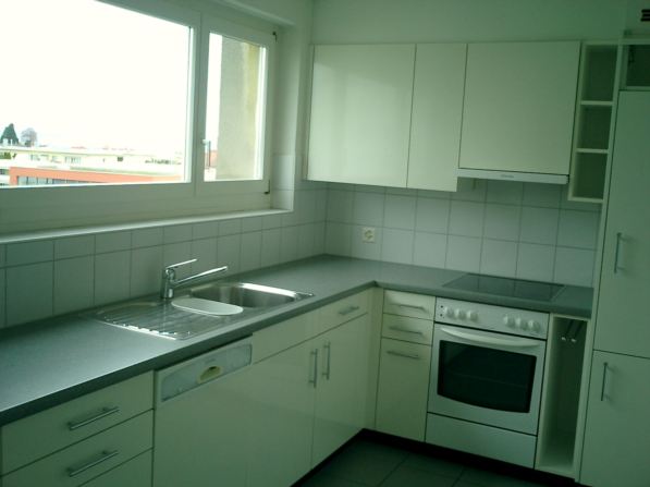 Modern kitchen with stainless steel appliances, white cabinets, gray countertops, sink with faucet, dishwasher, oven.
