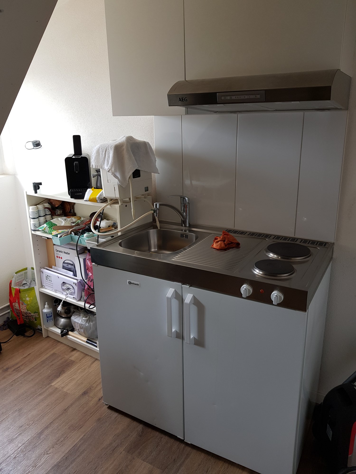 Compact kitchen with sink, induction cooktop, dishwasher, under cabinet fridge, overhead extractor