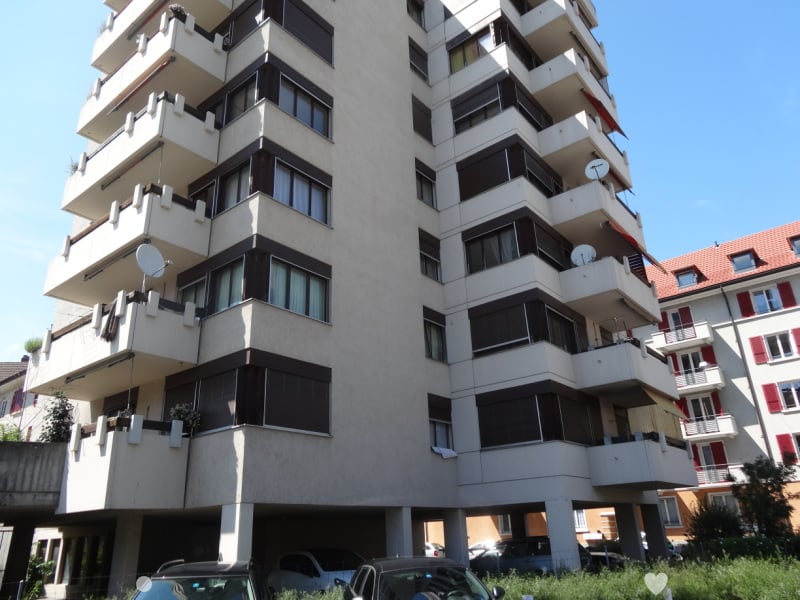 modern multistory building with multiple balconies, white walls, glass windows, underground garage