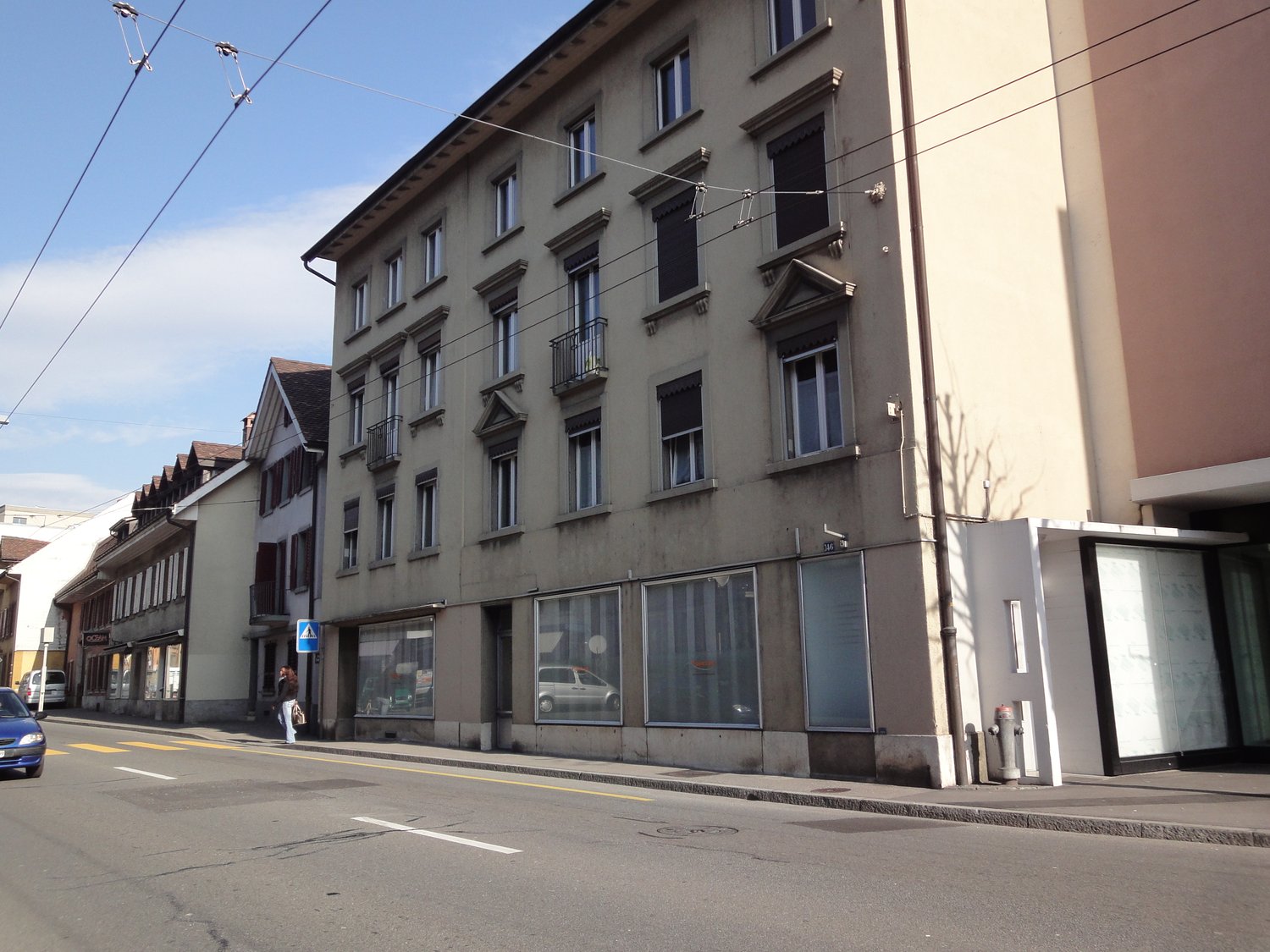 5 story building, windows, balconies, large glass windows on ground floor, street lights