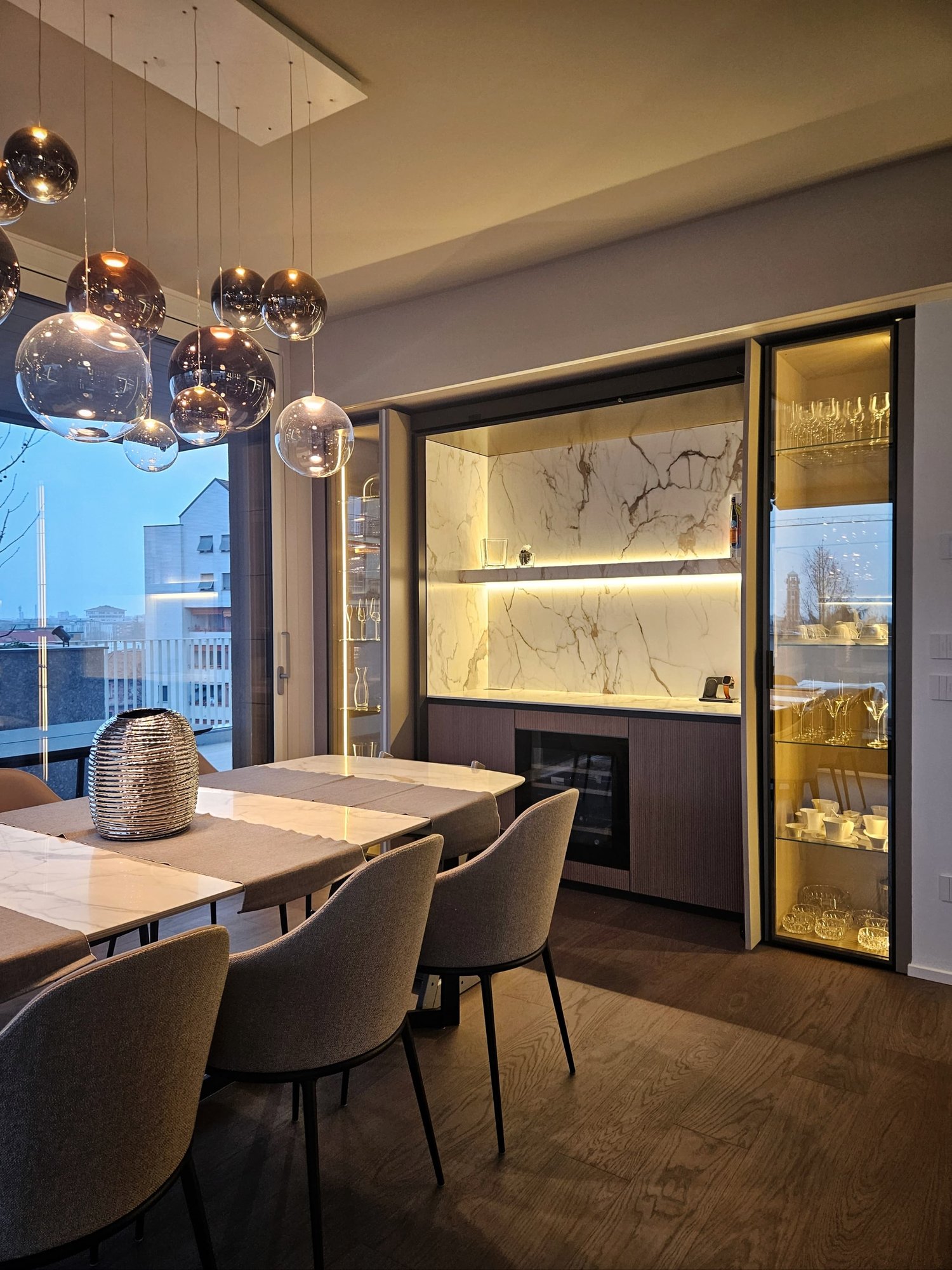 large dining table, 6 chairs, ceiling with light fixtures, marble wall, large windows, wine rack