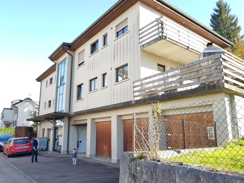 3-story apartment building with a balcony, garage, and fenced outdoor area