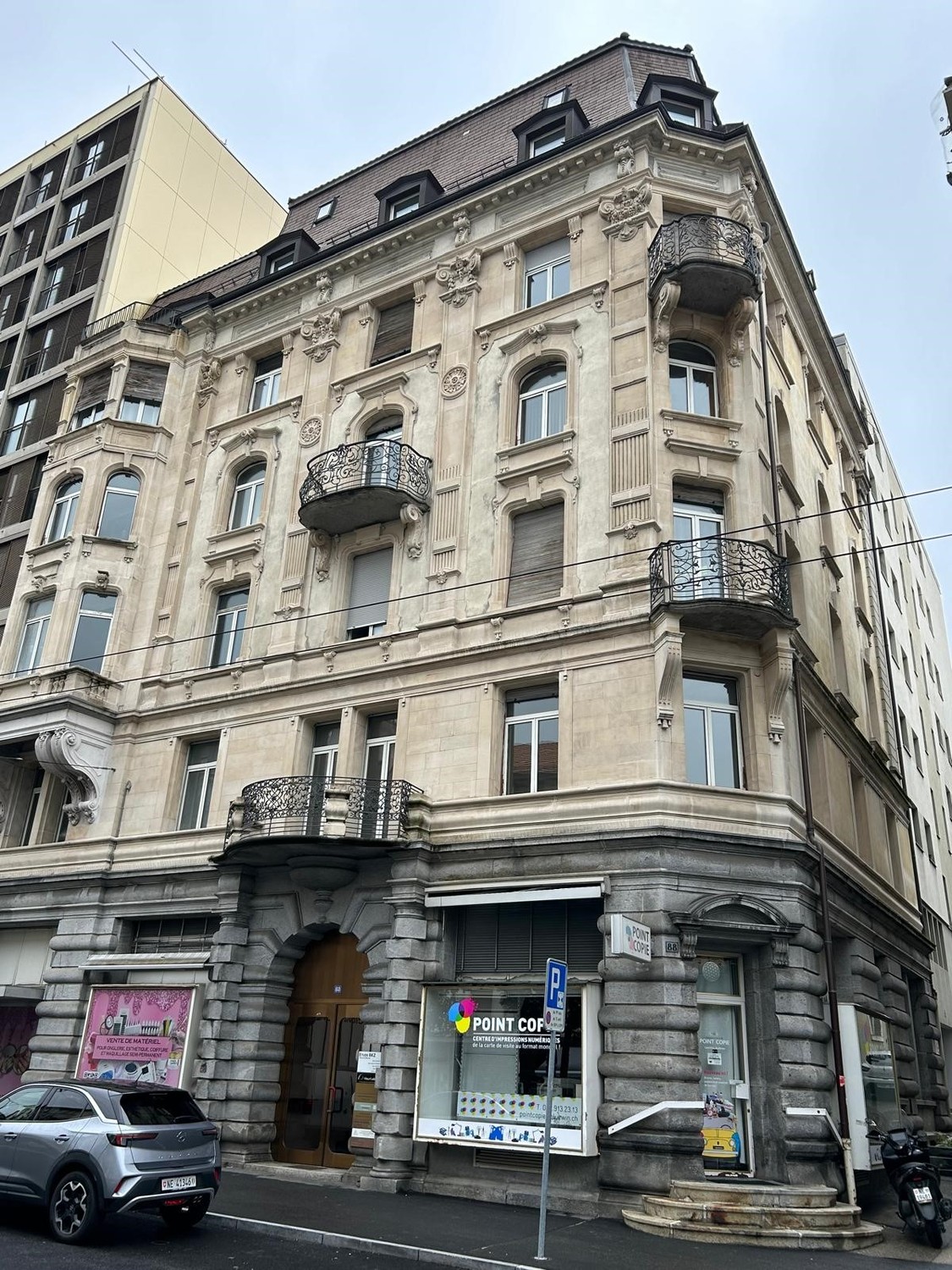 Multi-story building with ornate architectural details, including arched windows, decorative balconies, and intricate stone carvings. The building has a mix of modern and historic elements, with a Point Copy store on the ground floor.
