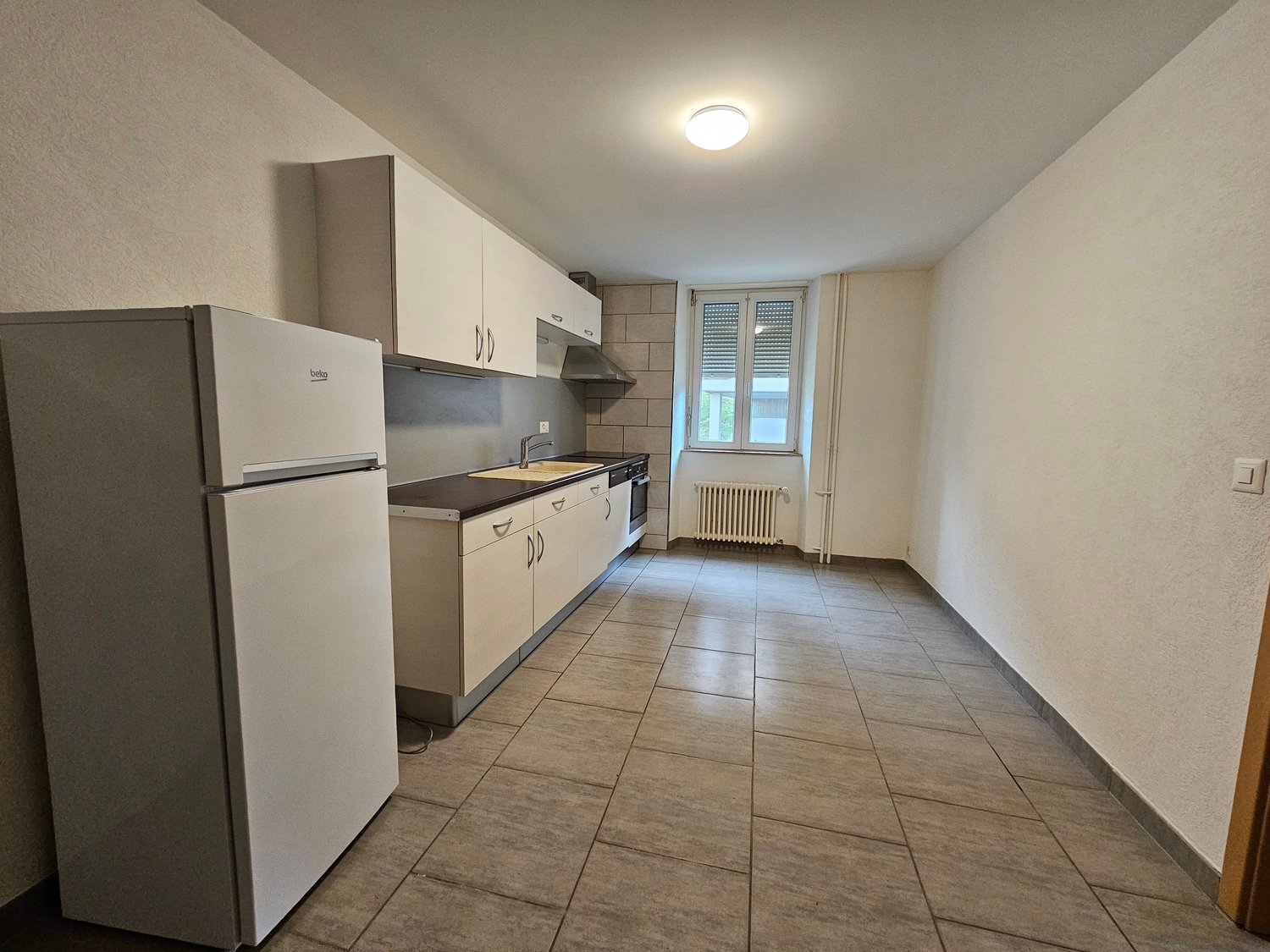 modern kitchen, tile flooring, white refrigerator, wooden countertop, modern appliances, built-in oven, open window, radiator