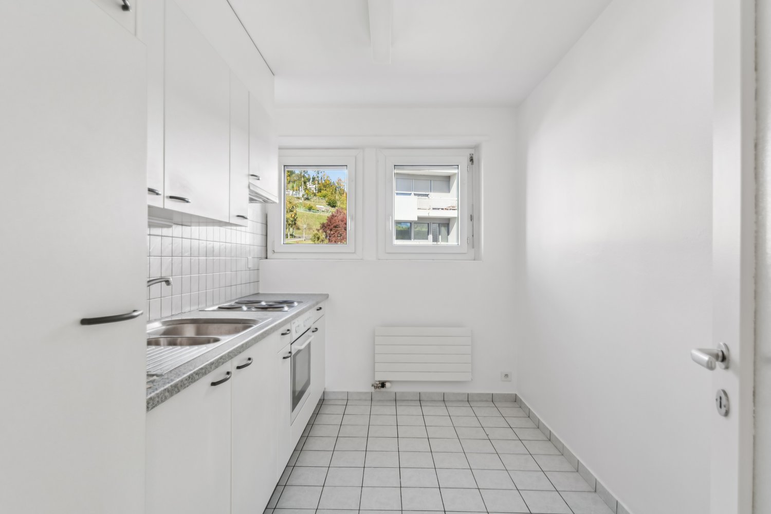kitchen area, sink, oven, gas stove, windows, tiled floor, white cabinets