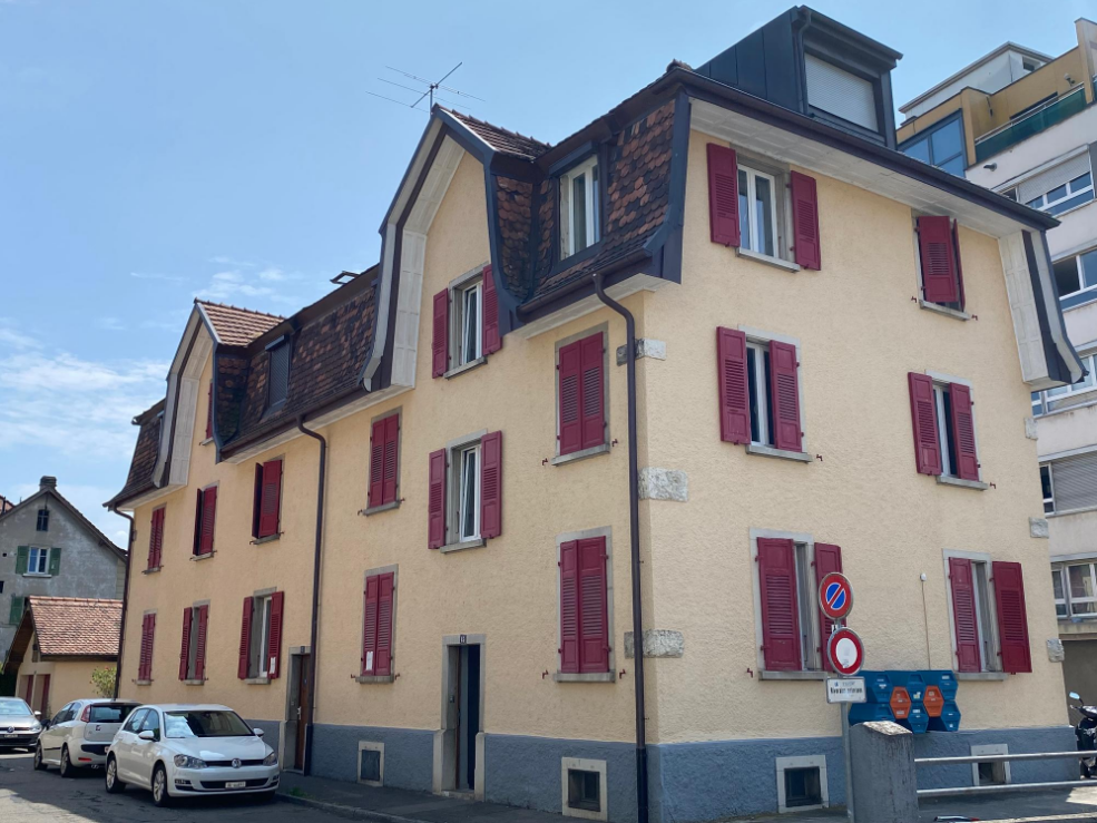 4-story building, brick facade, red shutters, windows with white frames, street sign, cars parked