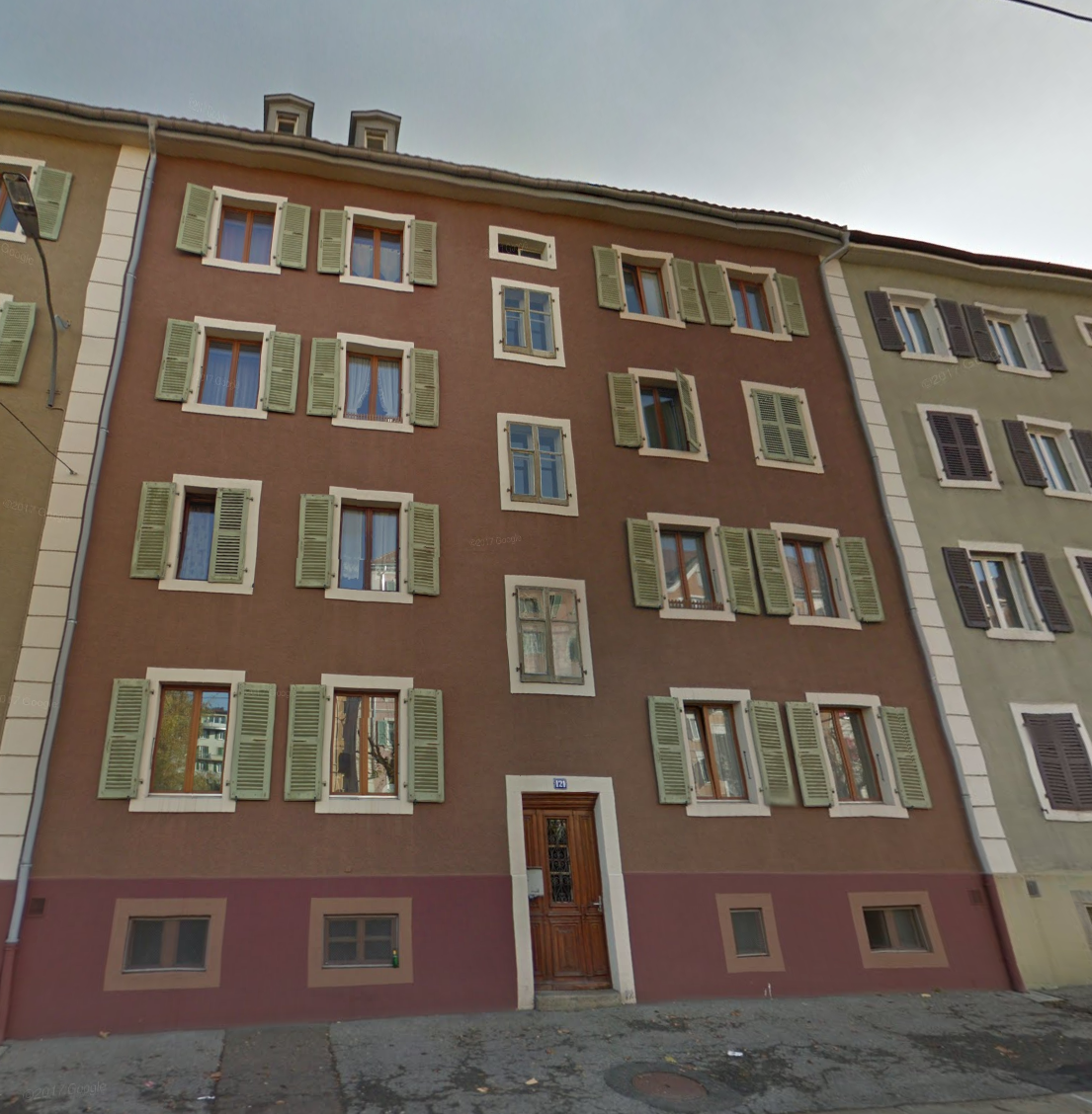 3 story building, brown walls, green shutters, wooden door, windows