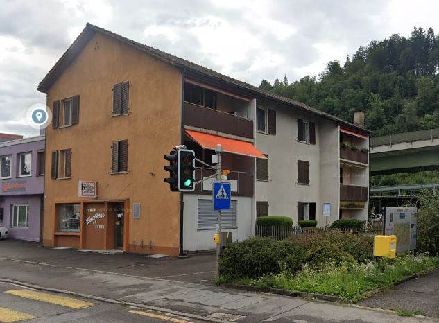 3 story building, brown and white paint, multiple windows, ground floor commercial with entrance, traffic light nearby