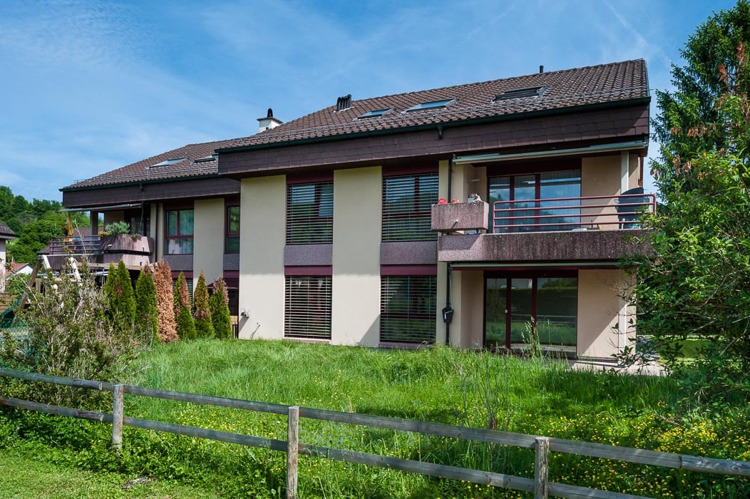 brown shingled roof, beige walls, multiple balconies, large yard