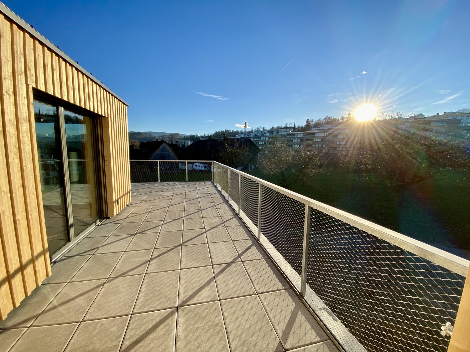 wooden railing, tile flooring, unobstructed view, sunny, large windows, metal grate