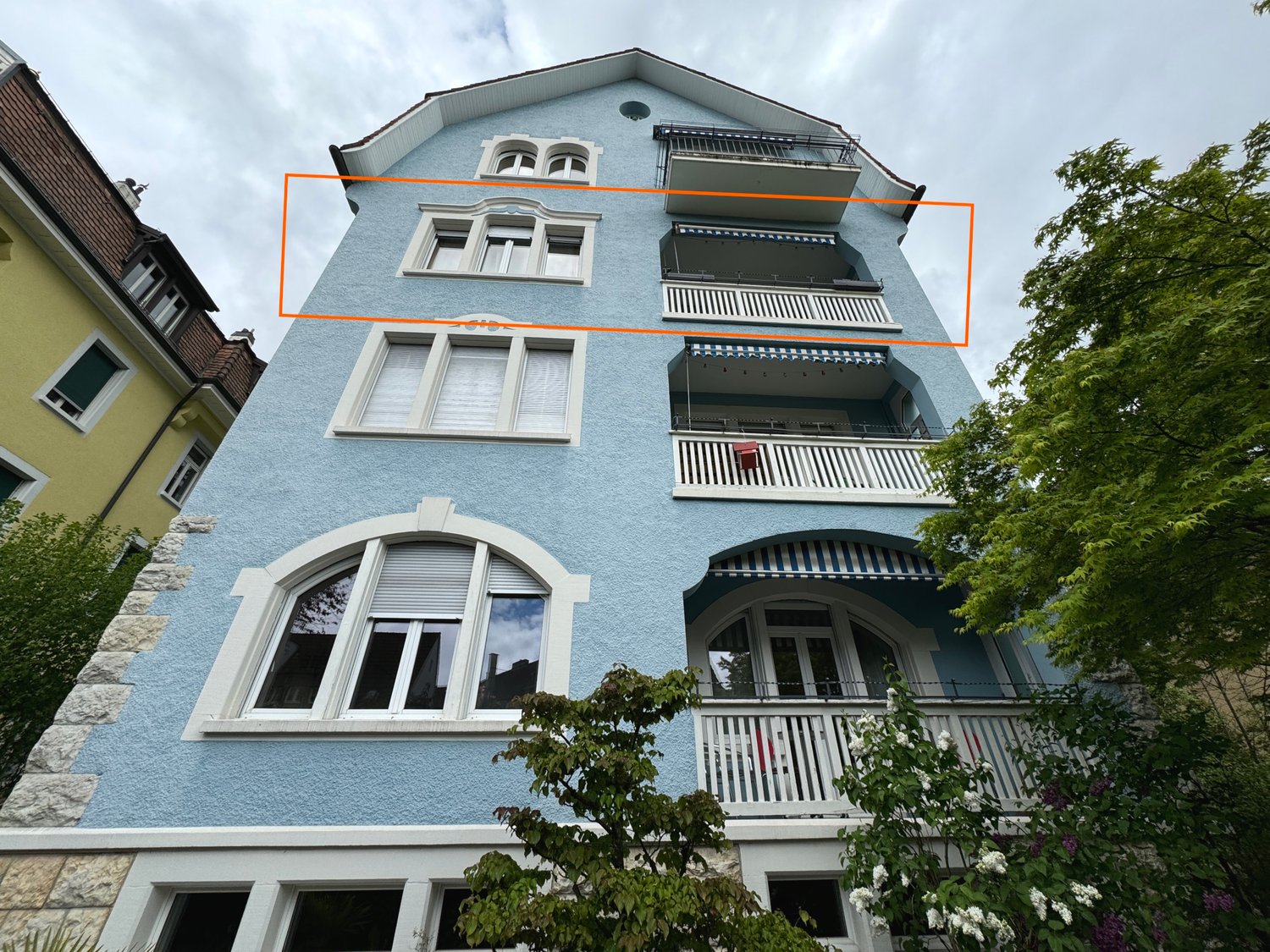 3 story blue building with balconies on each floor, arched windows on each floor