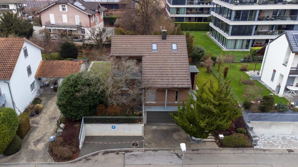 House with brown roof, garage, driveway, garden, neighboring houses