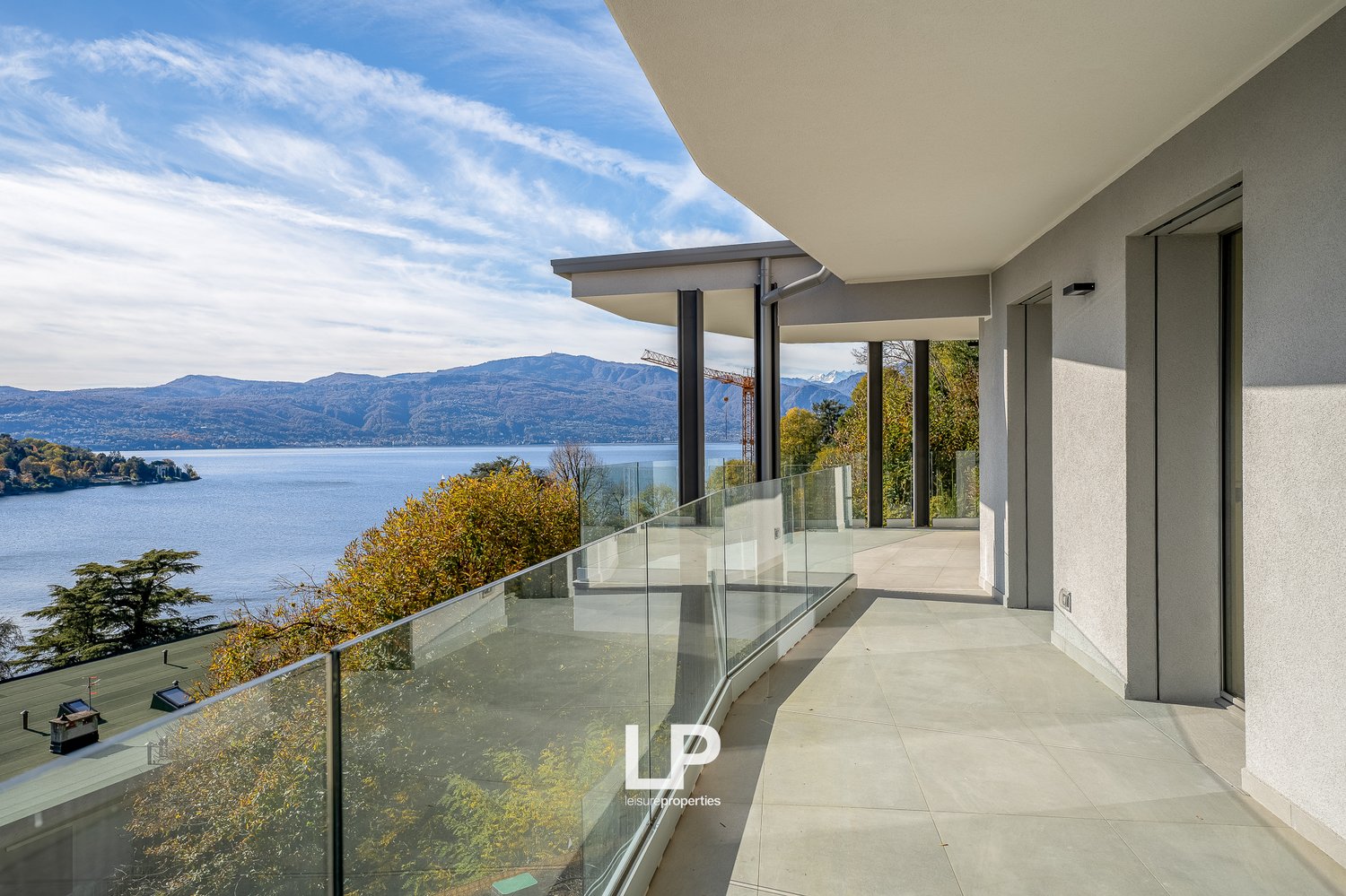 building exterior, glass railings, lake view, terrace, mountains in background