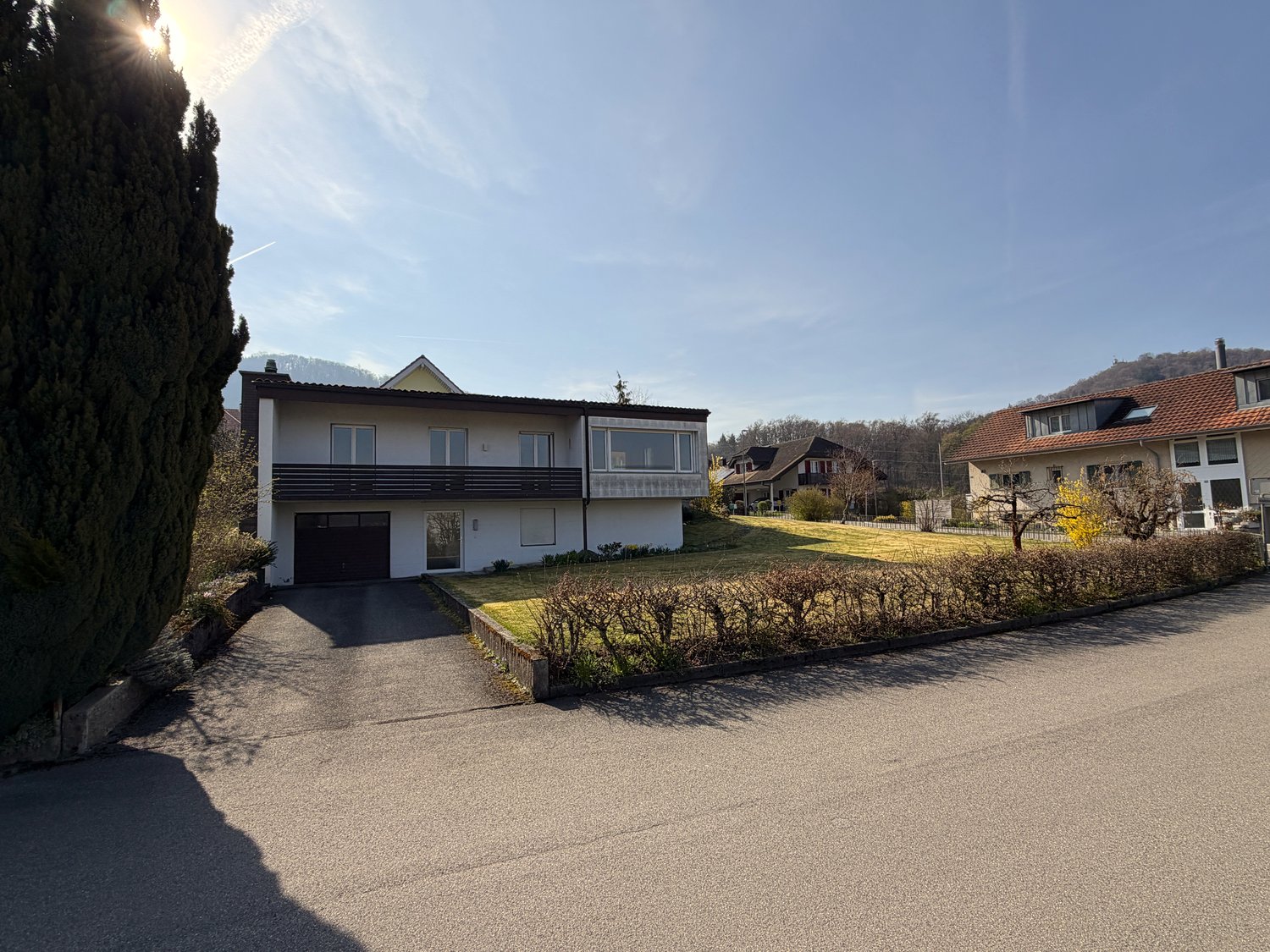2 story house, white exterior, garage, driveway, hedges, lawn, trees