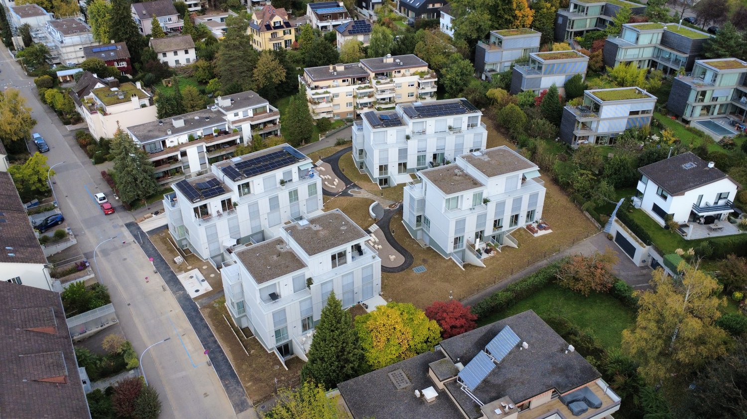 Multiple townhouses, solar panels on roofs, green roofs, driveways, parking spaces