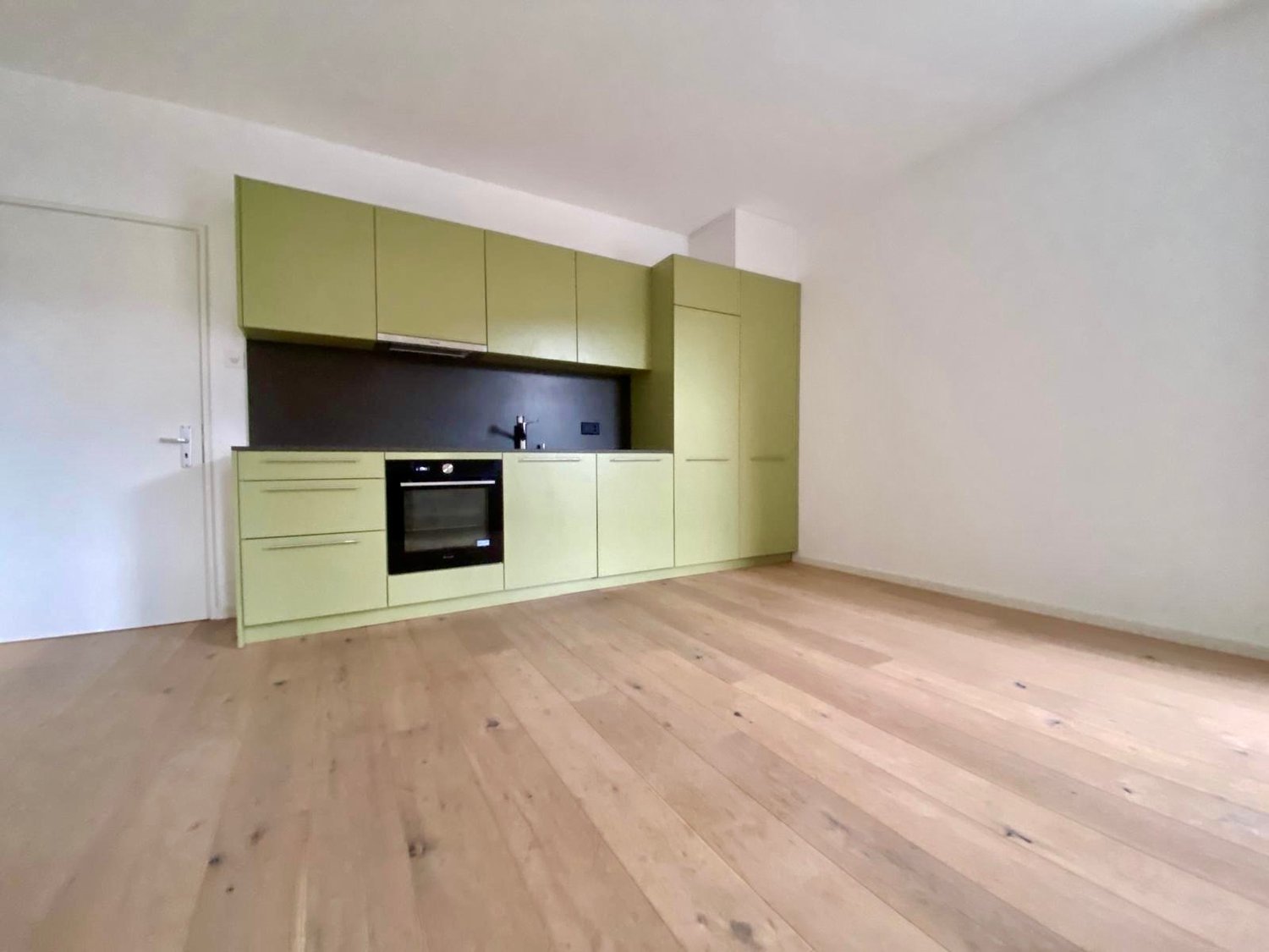 kitchen with modern design, green cabinets, white walls, wooden floor