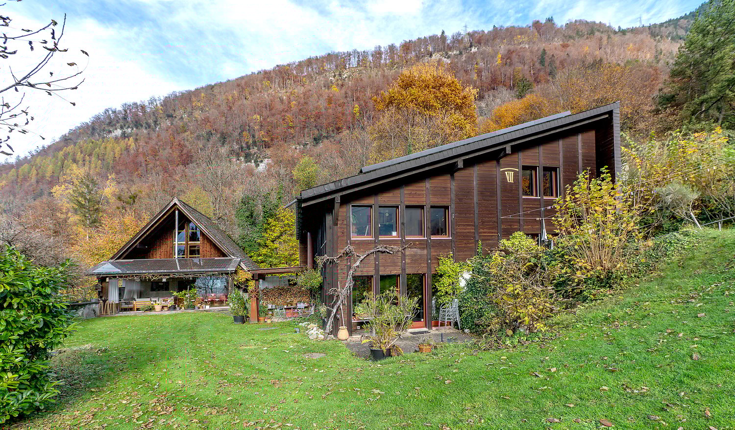 Wooden house, two storeys, on slope, green grass, garden, terrace, autumn landscape