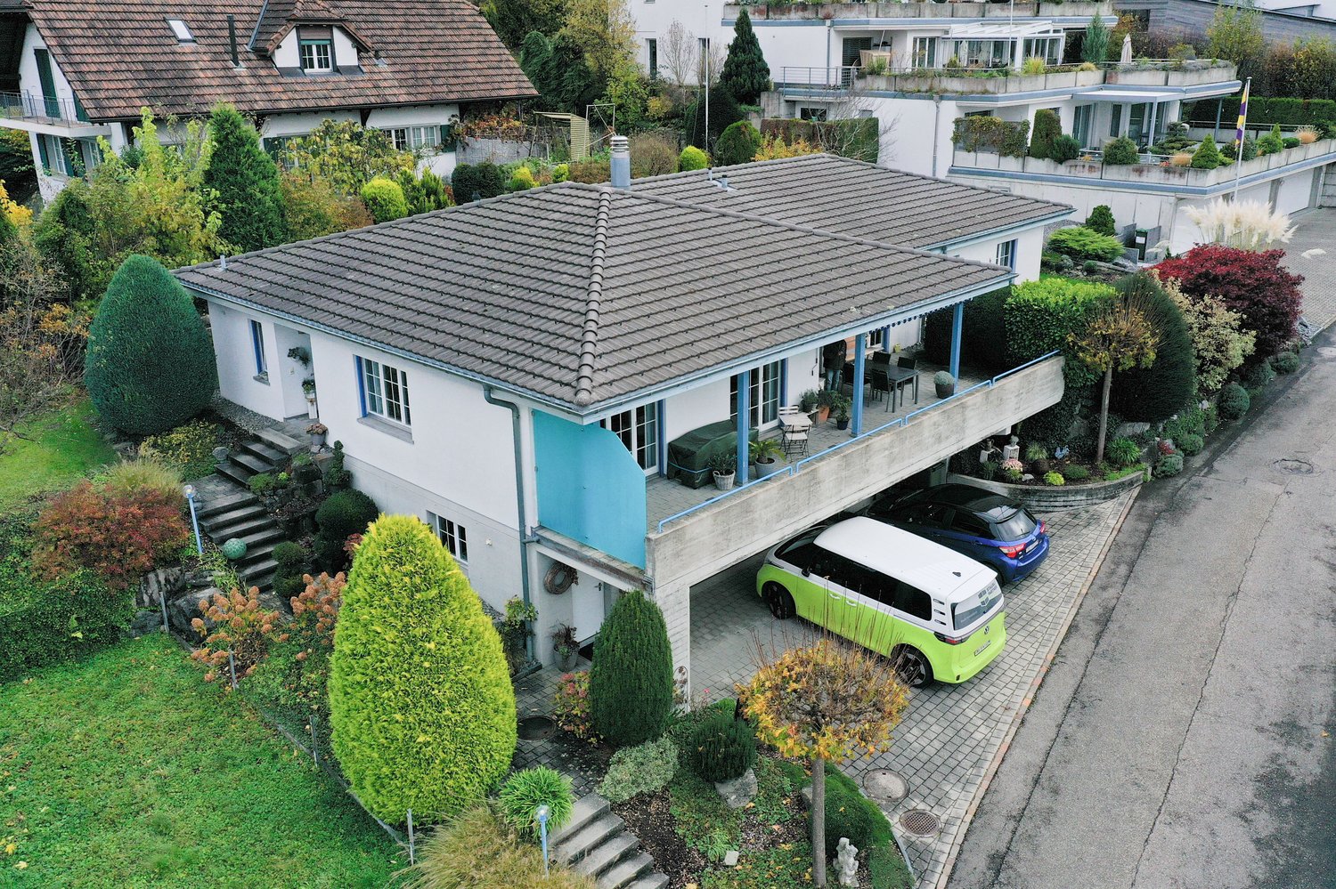 Two story house with garage, grey roof, white walls, blue trim, two cars parked