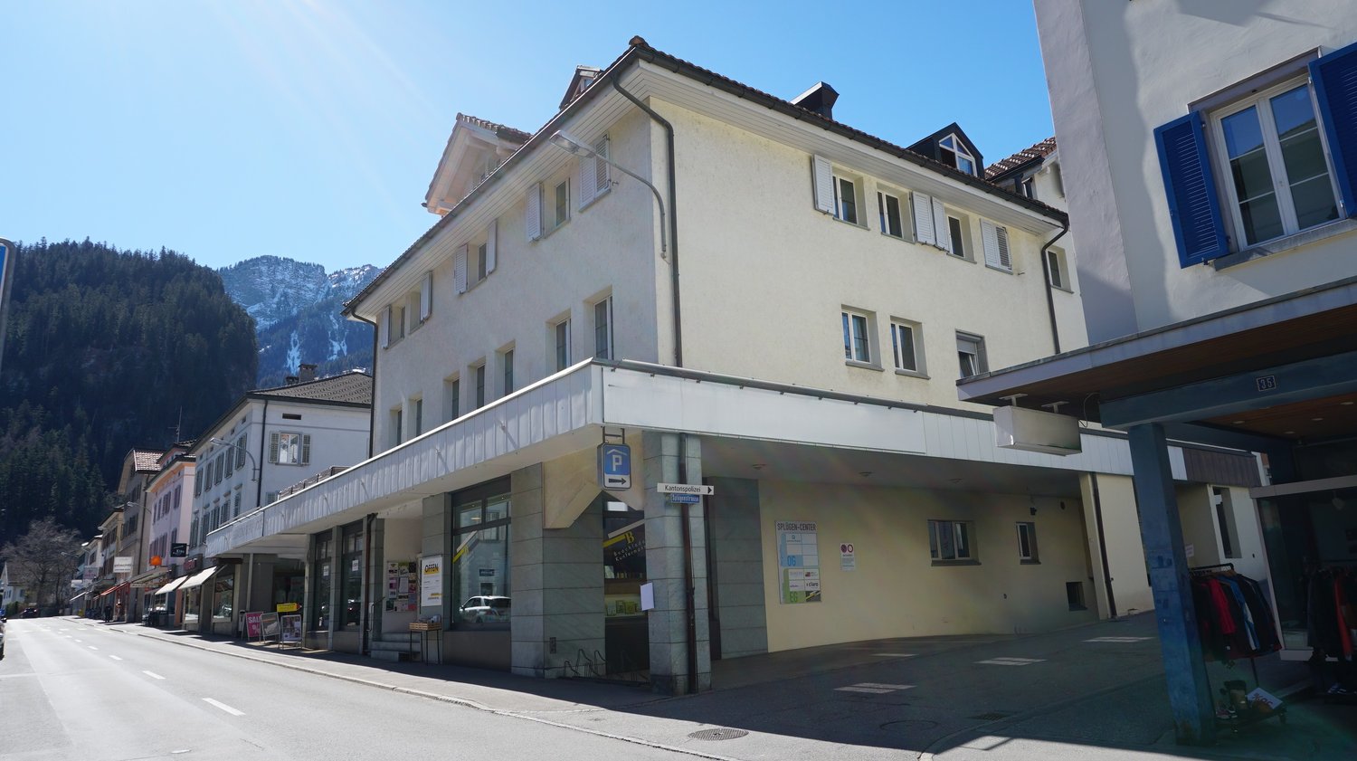 3-story building, white paint, multiple windows, awnings, car park sign, mountain view