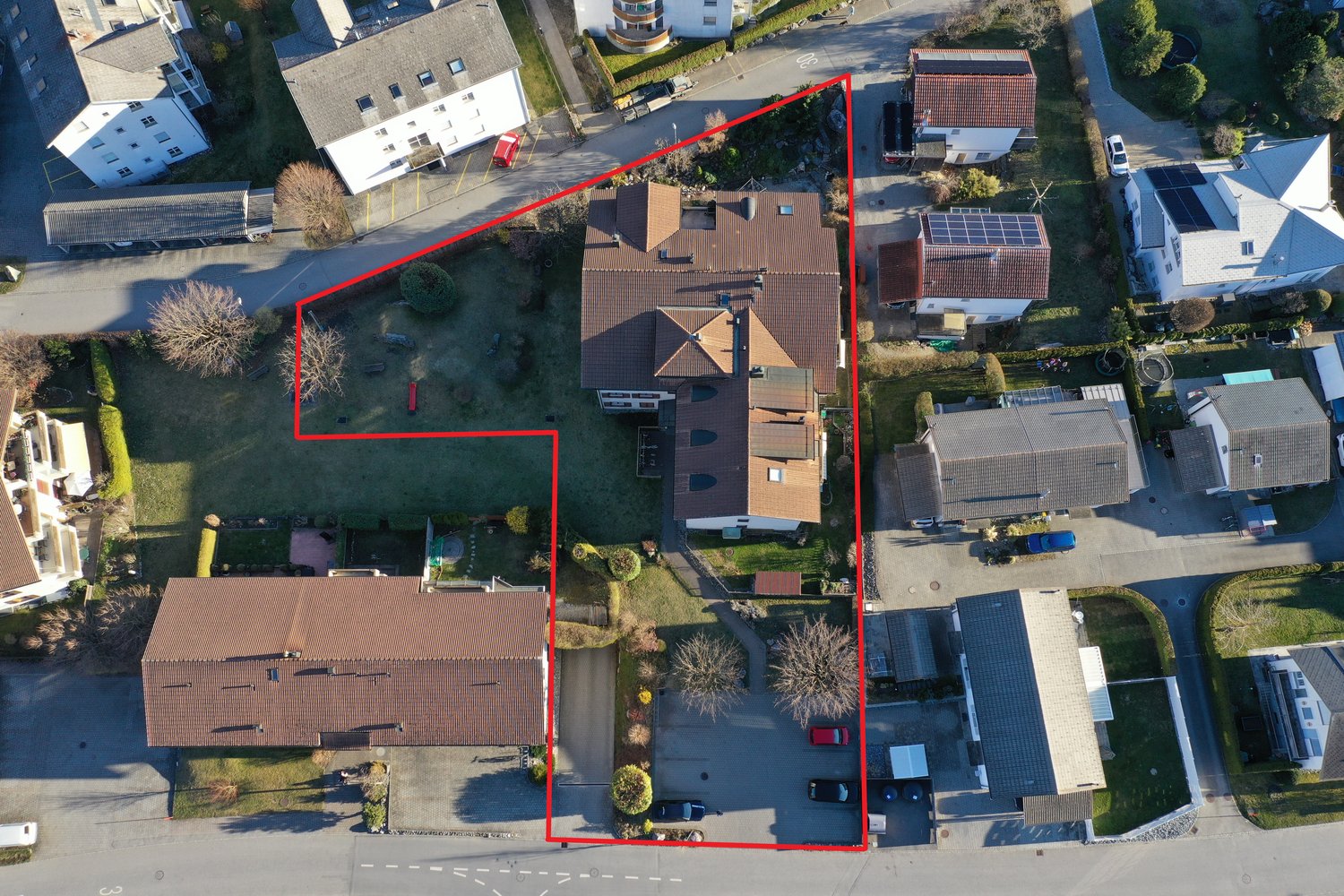 Aerial view of a two-storey house with a swimming pool and cars parked in front.