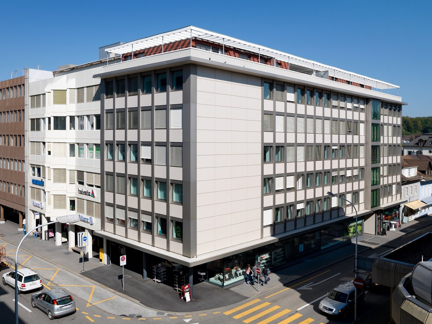 A building with multiple floors, several windows and multiple signs such as Helvetia and Allianz