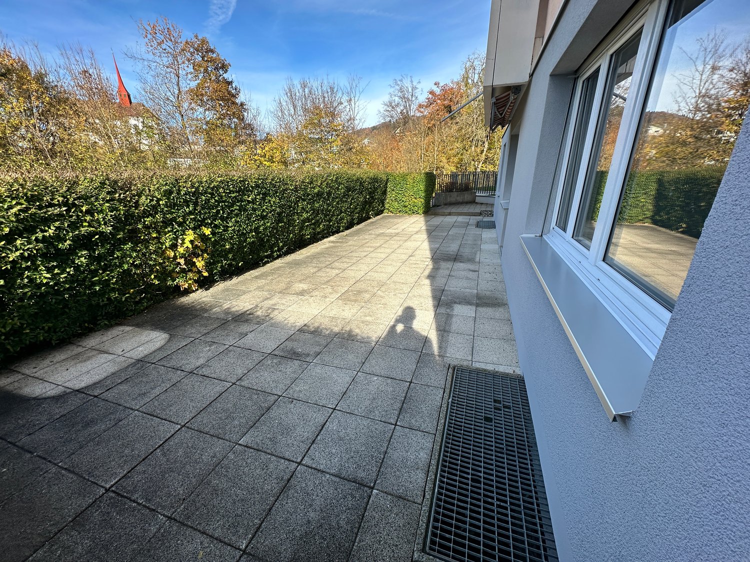 paved courtyard with tile flooring, shrubbery, small fence, drain cover
