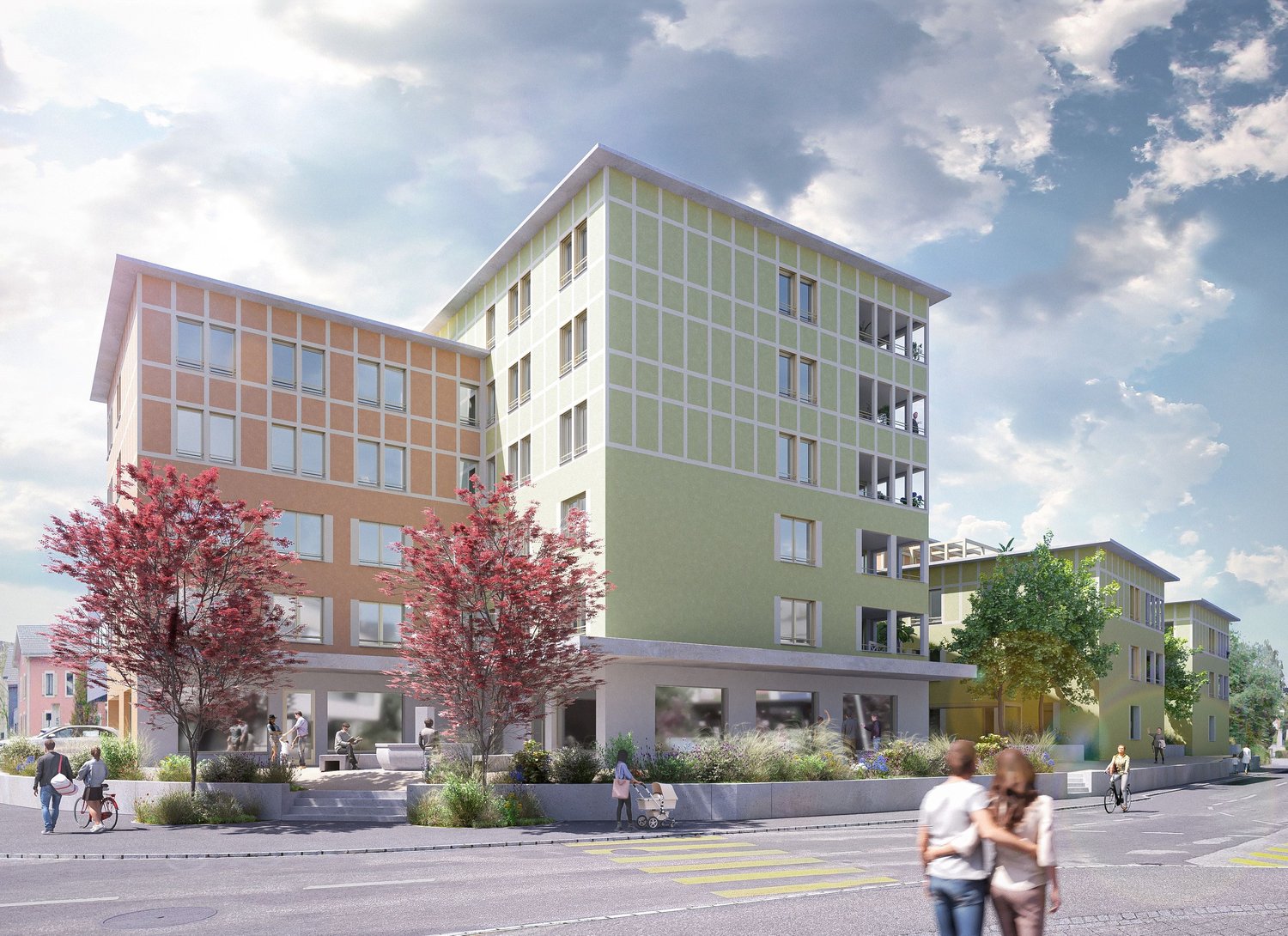 A multi-story building with a modern, glass-and-concrete design. The building has balconies on some floors and is surrounded by trees and landscaping. There are people walking in the foreground, suggesting a mixed-use or residential development.