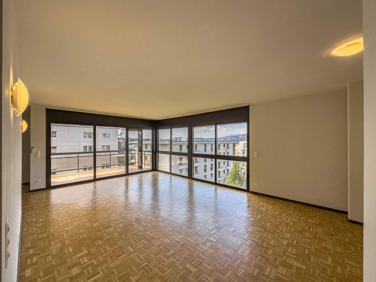empty room, wooden floor, sliding glass doors to balcony, mounted lights, large windows