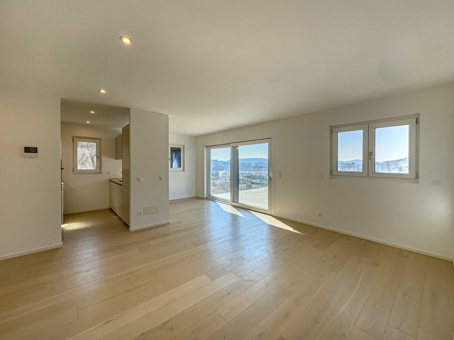empty room with white walls, wooden floors, glass sliding doors, windows, white ceiling with lights