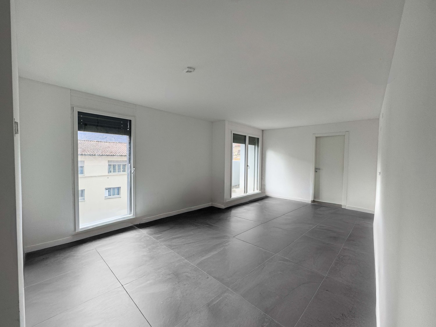 empty room, gray tiles, white walls, large windows, natural light