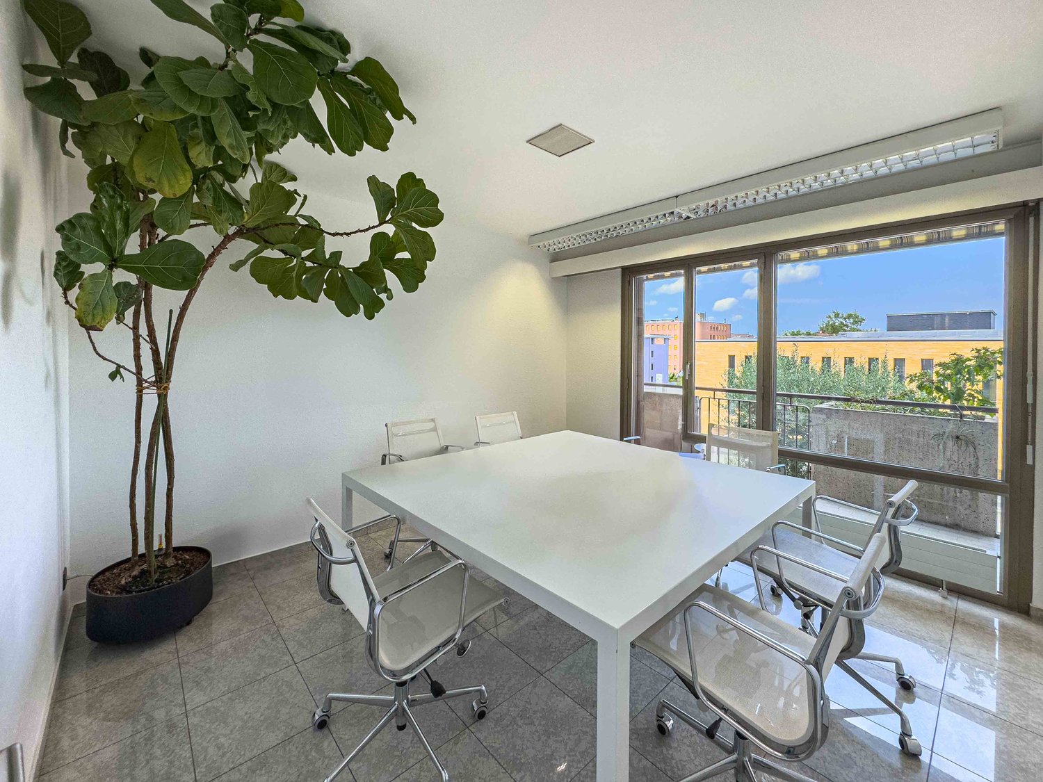 large white table, white swivel chairs, white walls, balcony, large plant
