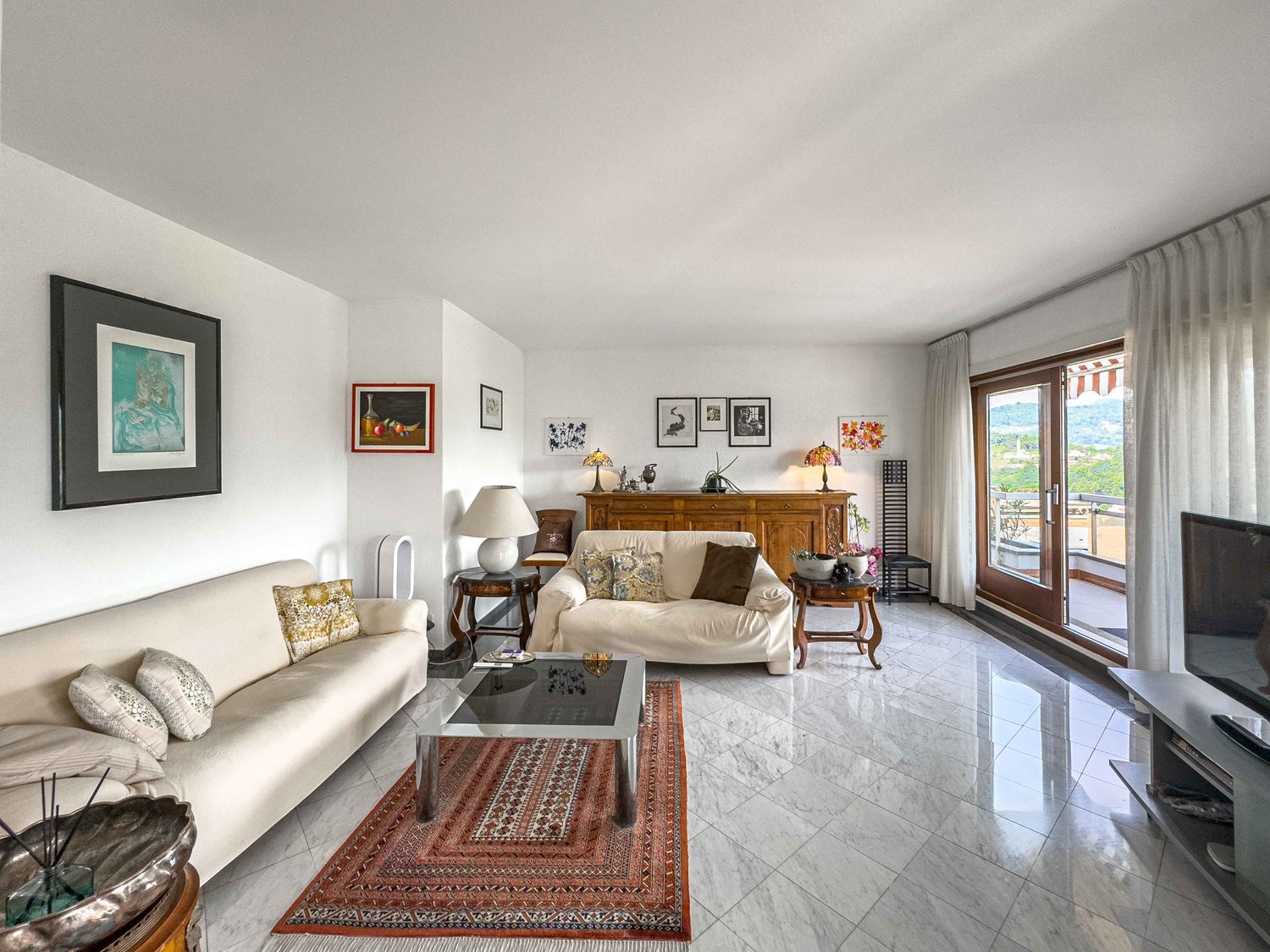 2 sofas, center table, lamps, coffee table, television, large windows, rug, framed pictures, wooden cabinet