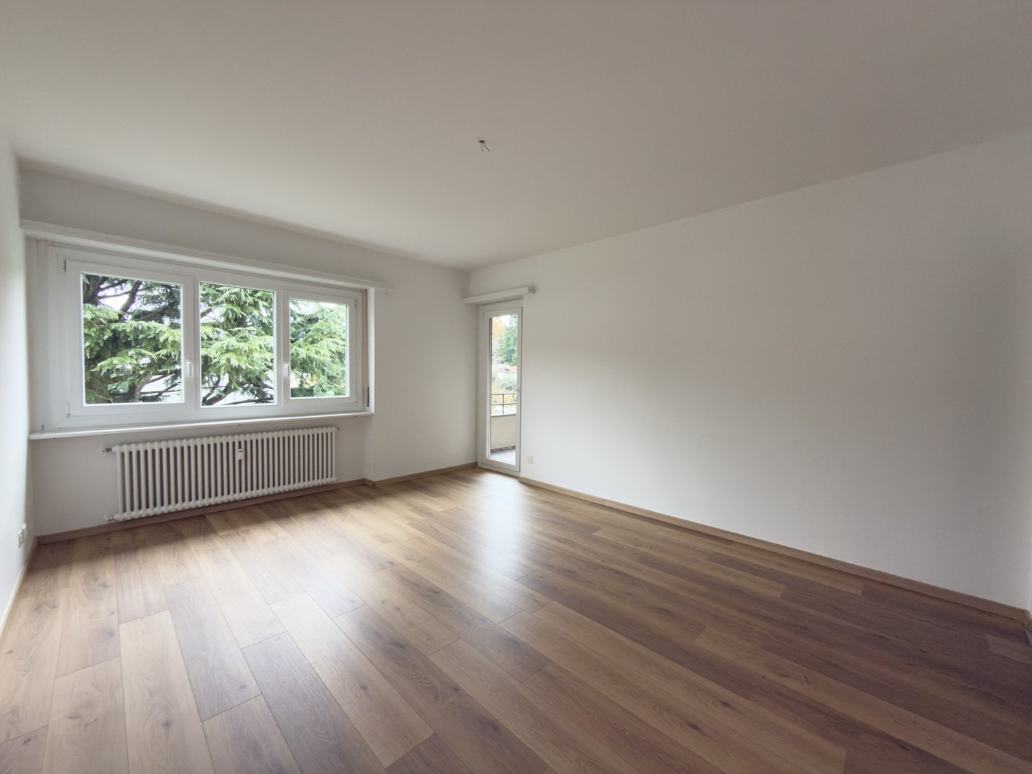 empty room, white walls, wooden floors, sliding glass door, windows with view