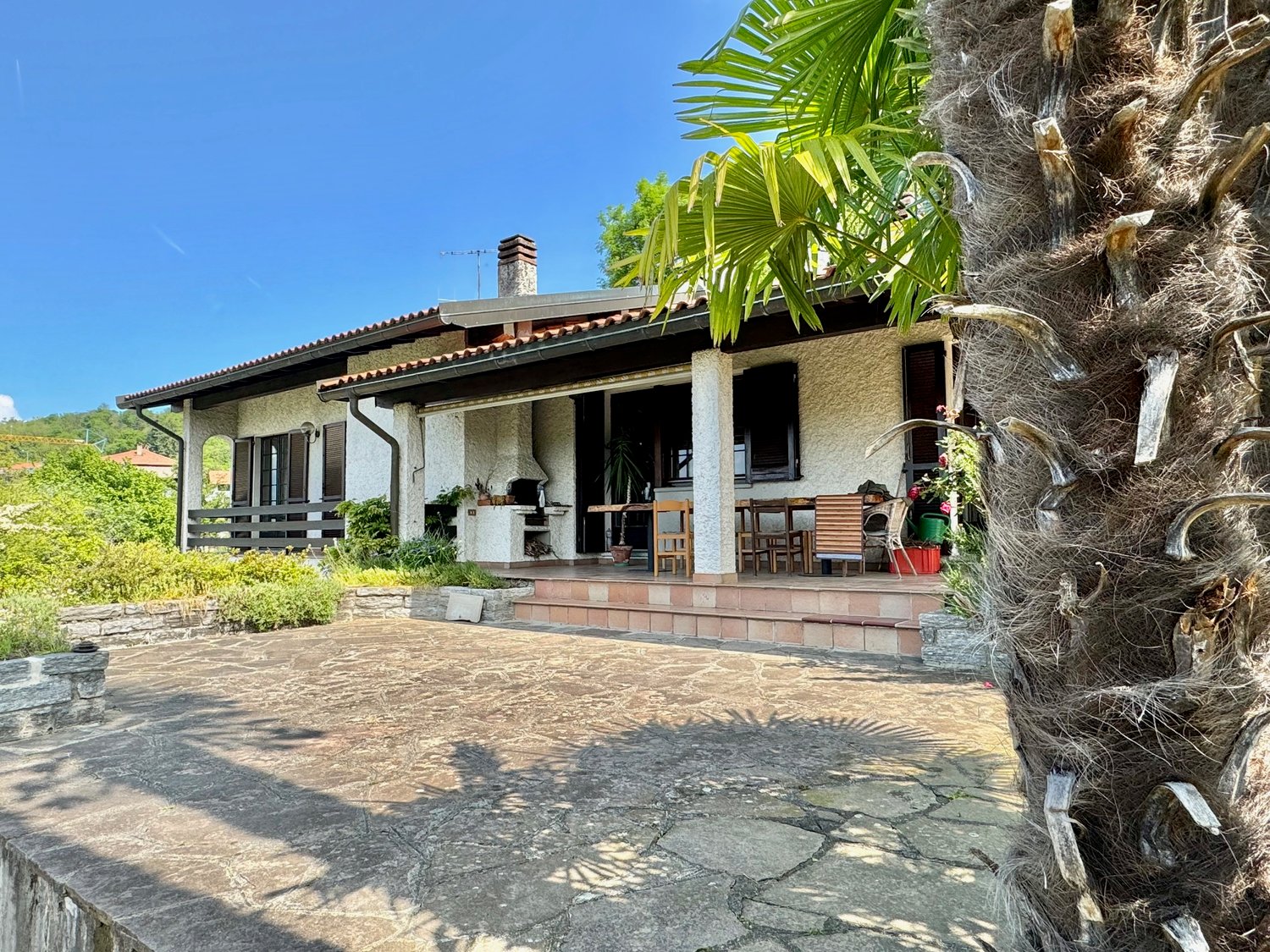 single story house, white exterior, red tiles, large patio, outdoor seating area, palm tree