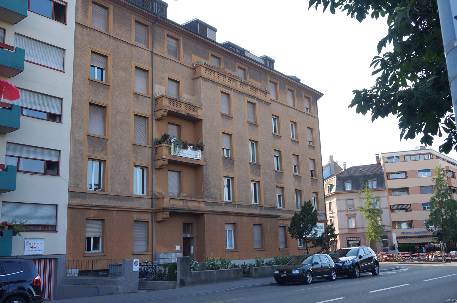 Multi-story residential building, multiple balconies, windows, brick facade, bicycle parking, entry doors