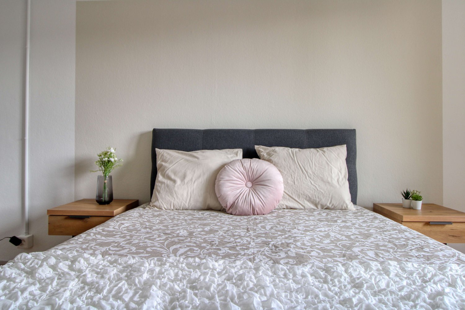a bed, pillows, flowers in vase, bedside tables, power outlet