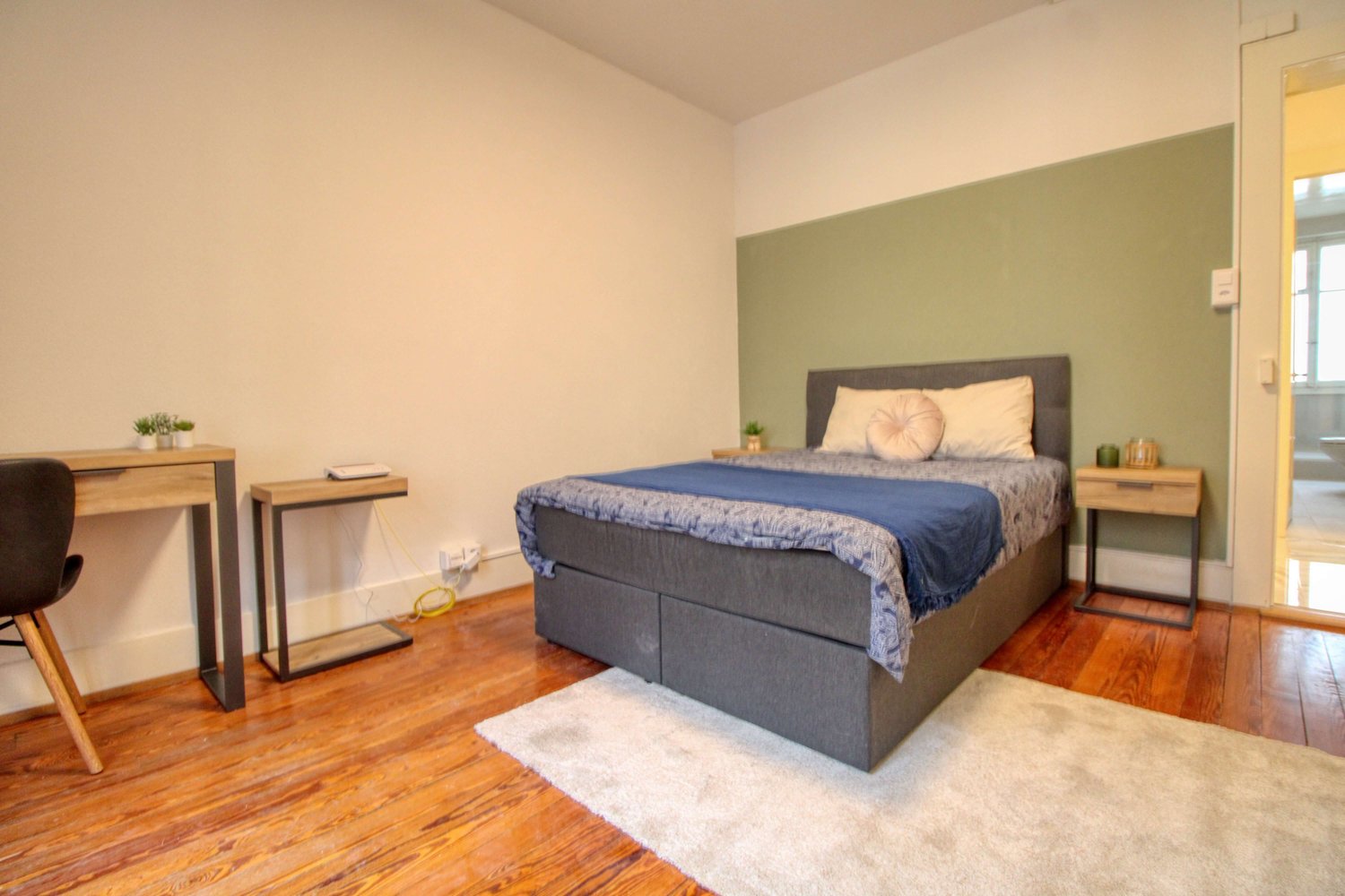 Wood floor, double bed, nightstands, desk, chair, carpet, pillows, plants