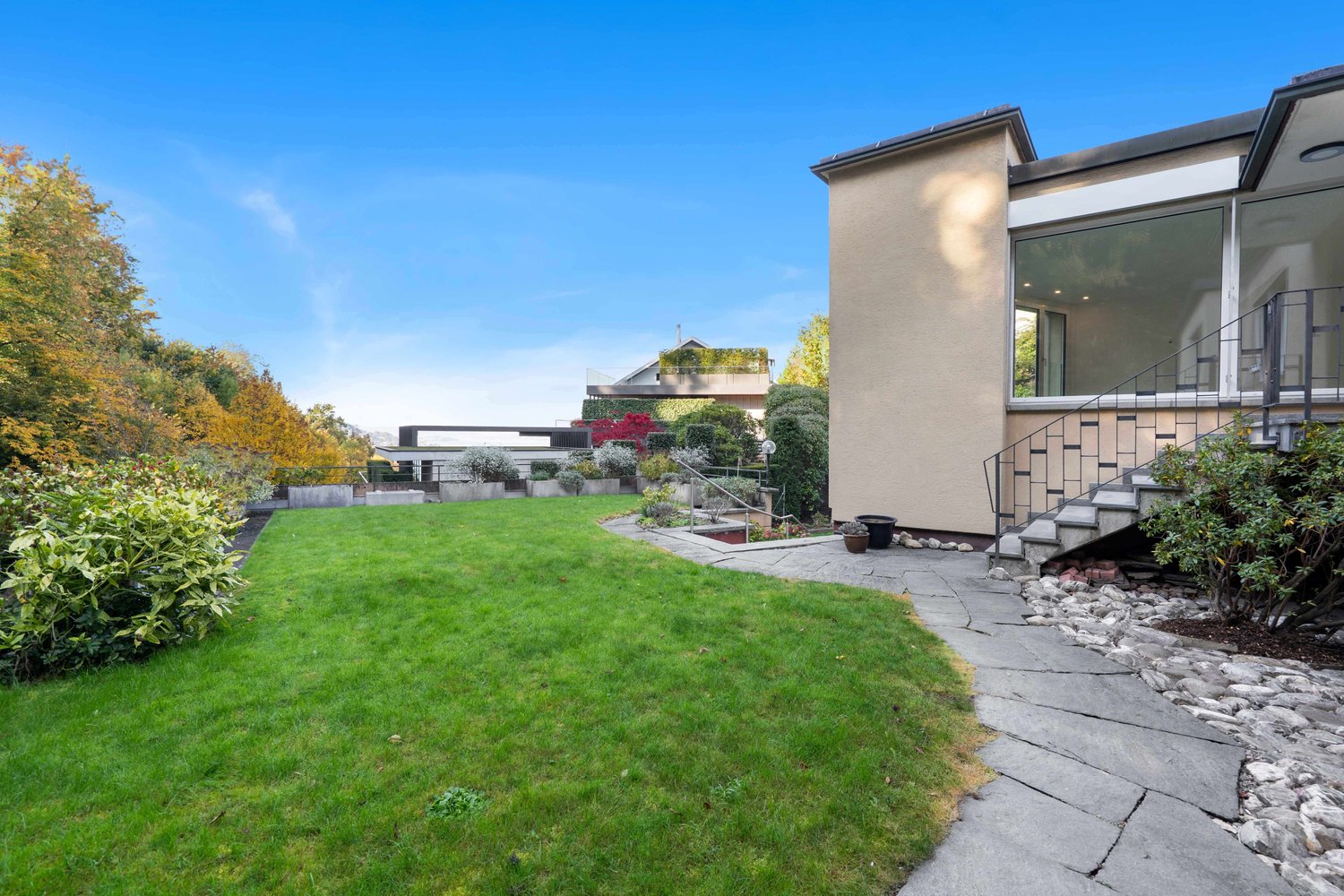 Spacious lawn, stairs leading to the terrace, paved path, shrubs, plants, trees